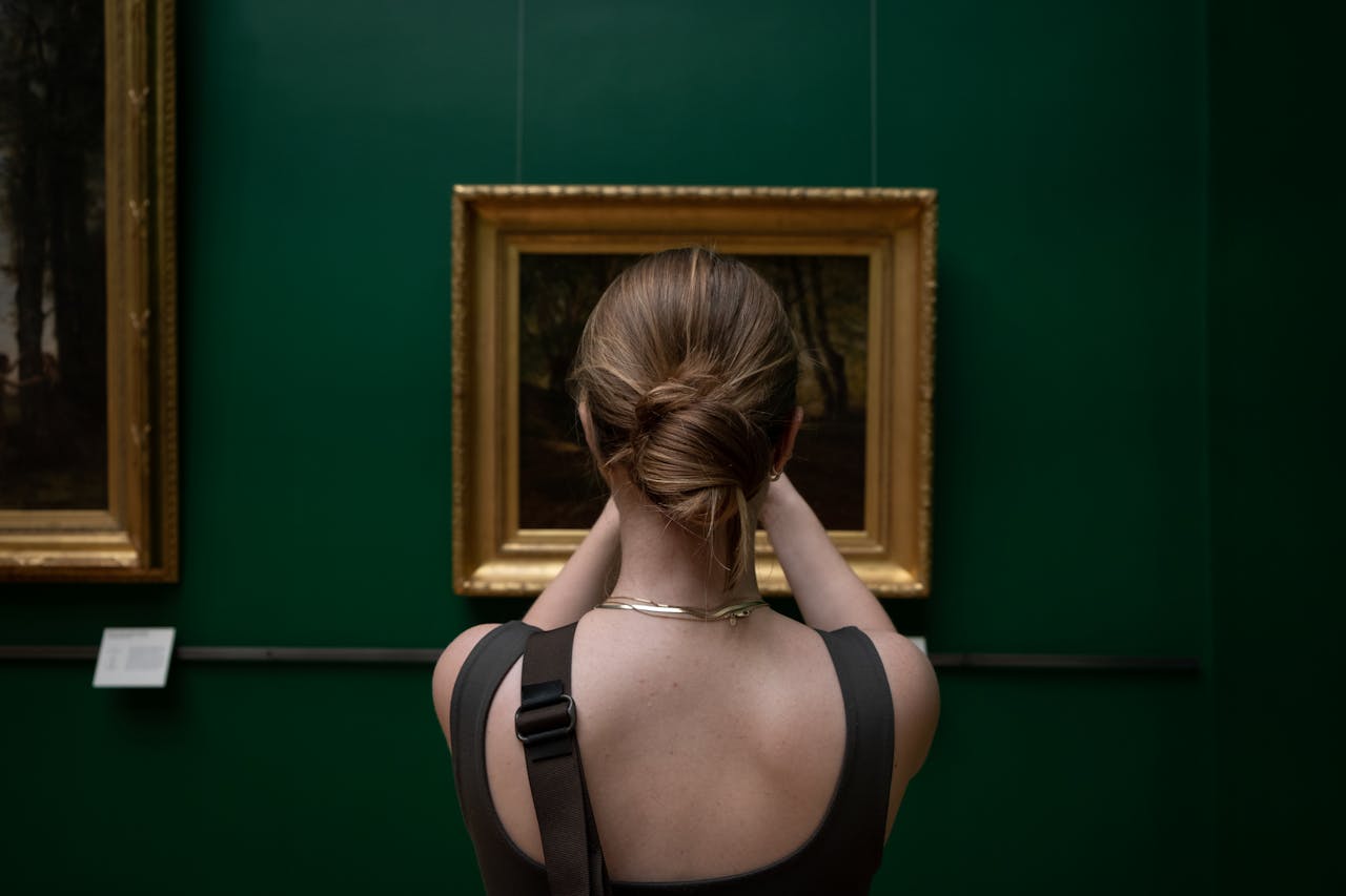 services-03 Back view of a woman photographing a painting in an art gallery.