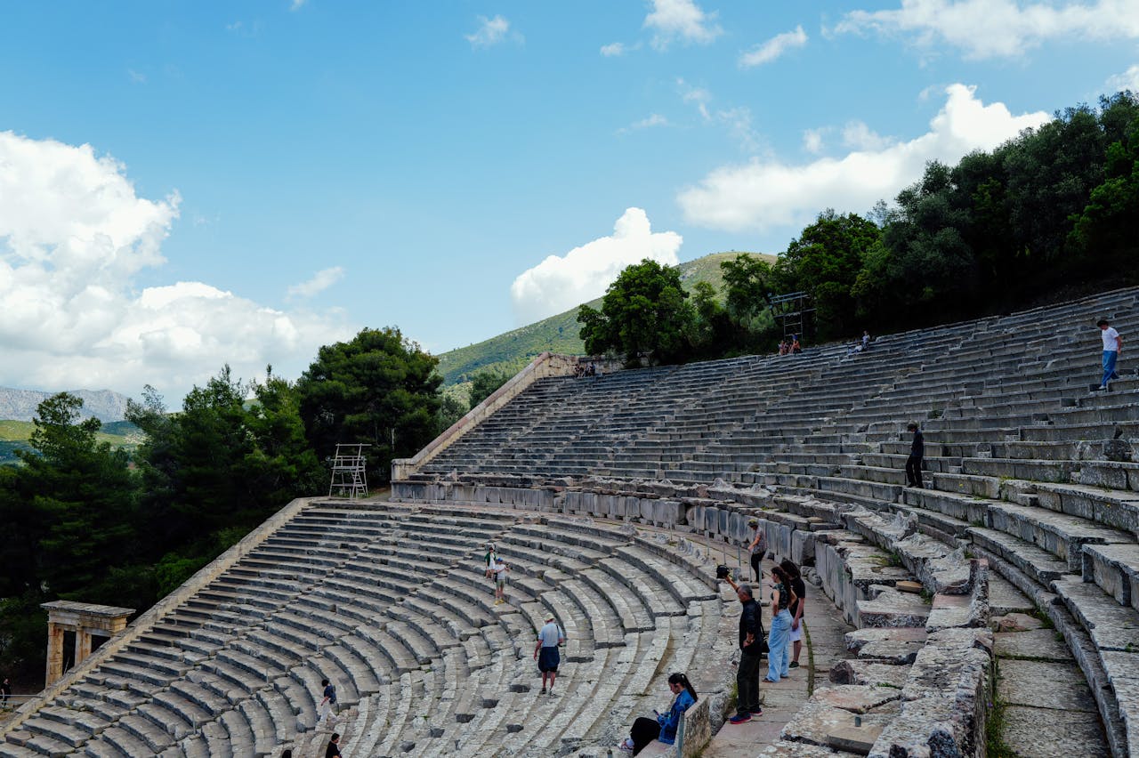 services-01 View of the Ancient Theater of Epidaurus with tourists wandering and capturing photos.