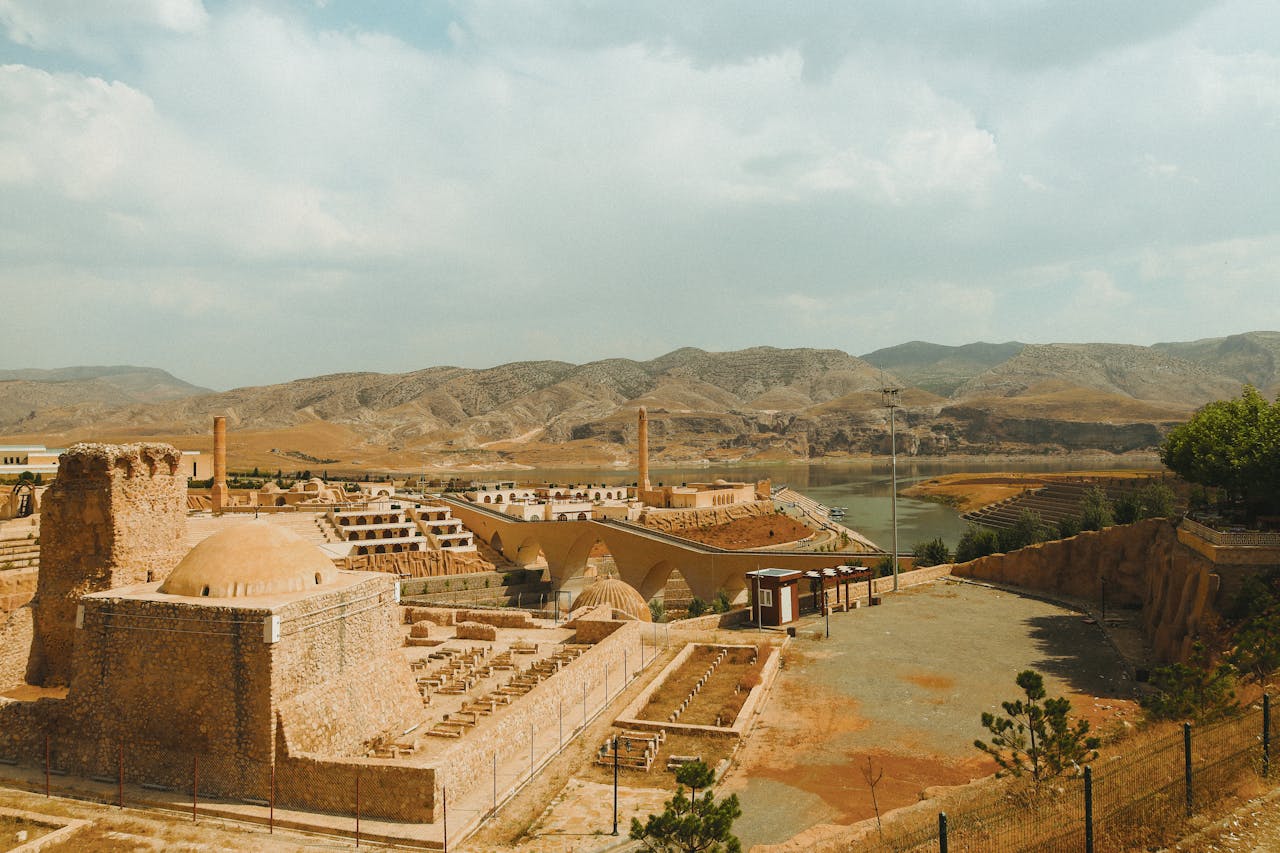 services-02 Explore the ancient ruins set against a backdrop of mountains and a winding river under a bright sky.